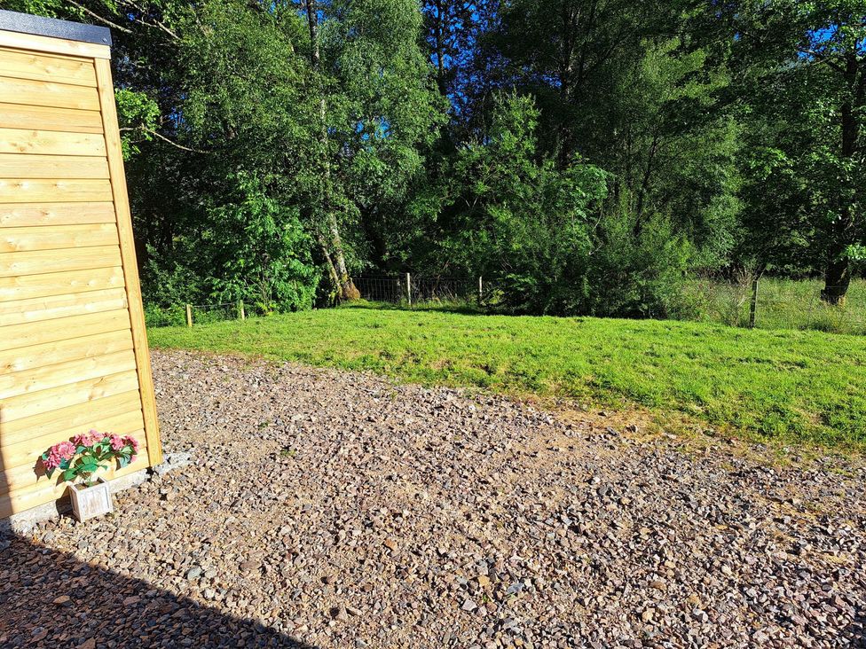 An outdoor area with a wooden wall and a planter at The Posh Bothy 2 Roy Bridge