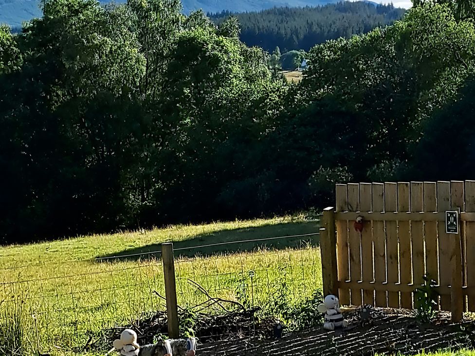 A fenced area with a wooden gate and stuffed animals at The Posh Bothy 2 in Roy Bridge