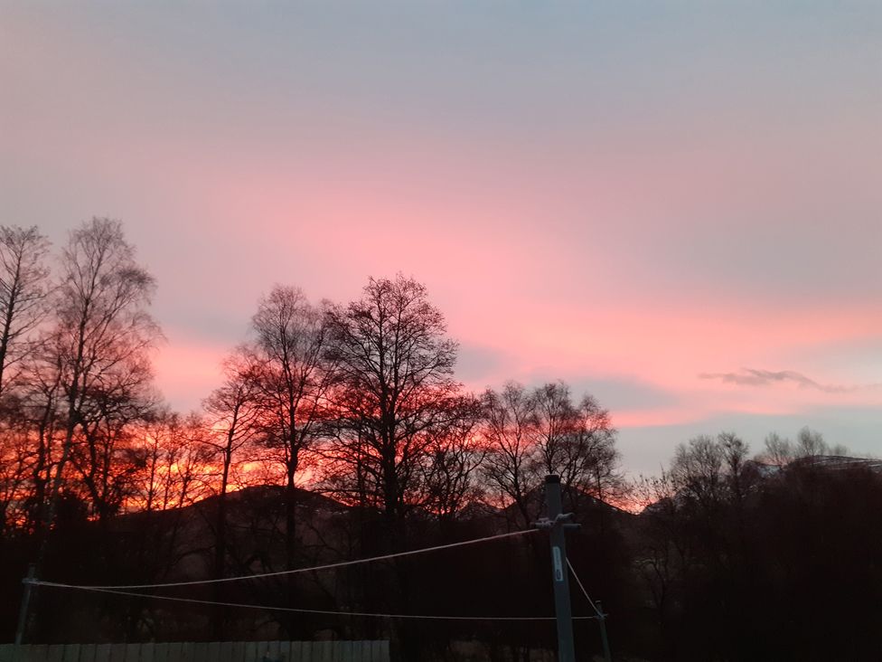 A sunset over trees and mountains at The Posh Bothy 2 in Roy Bridge