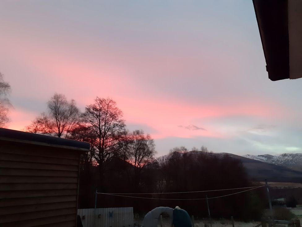 A view of the sky during sunset with trees and mountains at The Posh Bothy 2 Roy Bridge