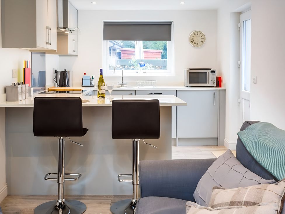 A kitchen with bar stools and microwave at Shedog Cottage in Isle of Arran