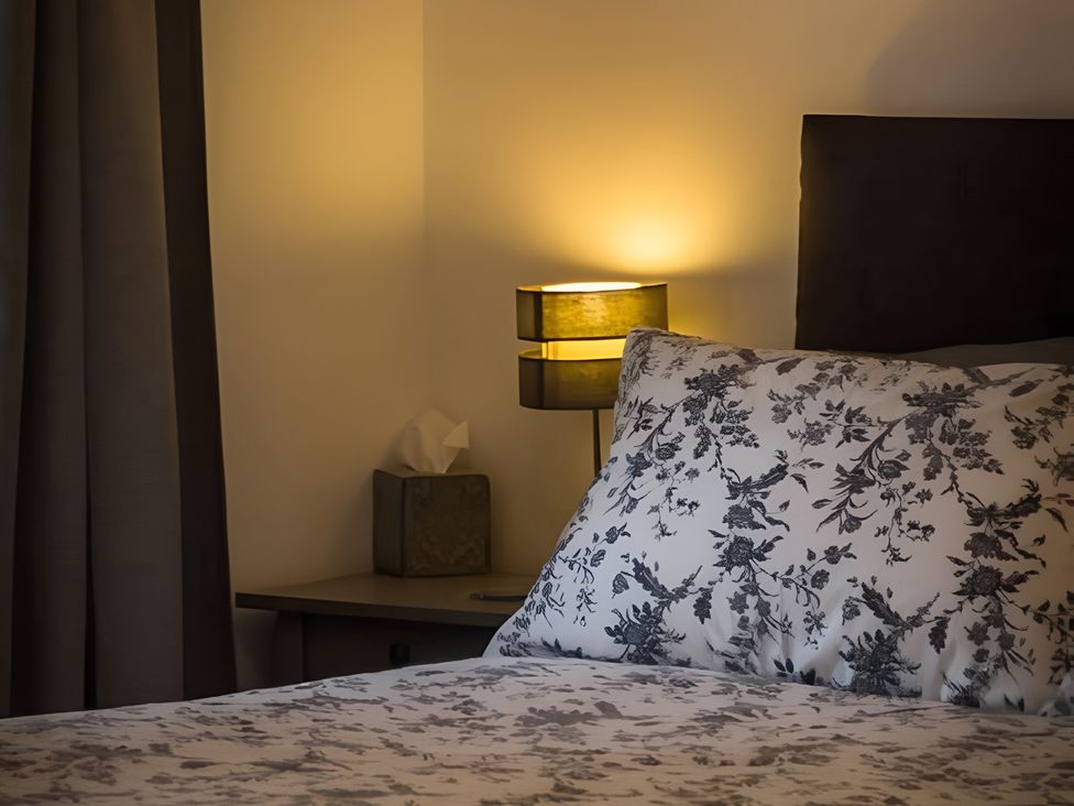 A bedroom with a bed and bedside lamp at Shedog Cottage, Isle of Arran