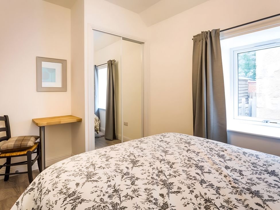 A bedroom with a bed and a chair at Shedog Cottage in Isle of Arran