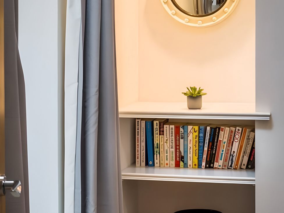A nook with books on a shelf and a plant at Shedog Cottage, Isle of Arran