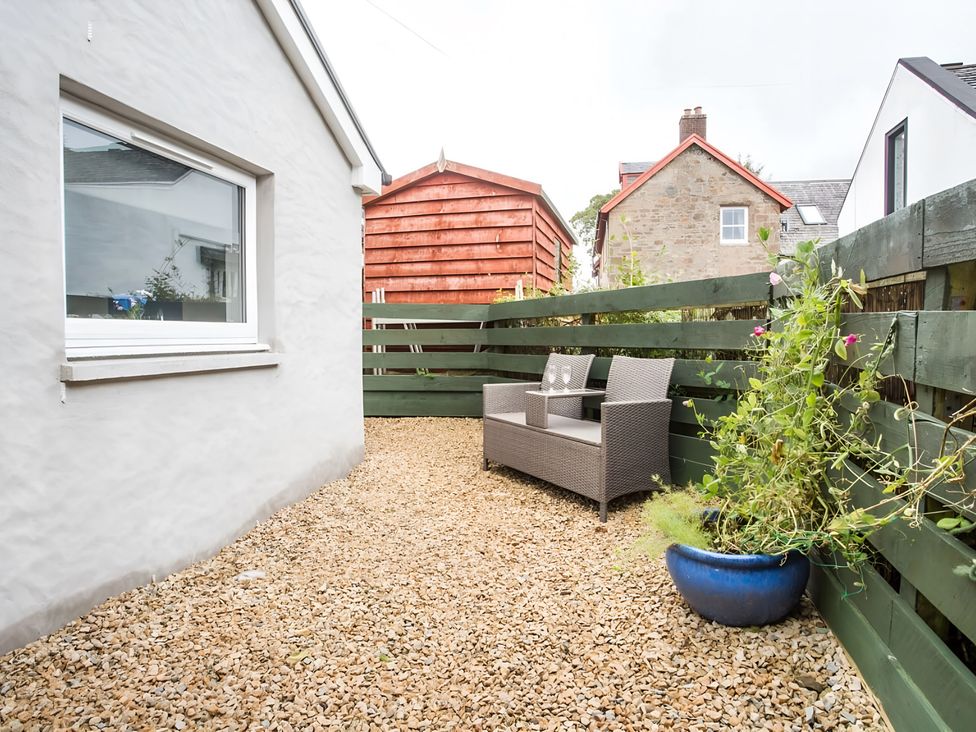 An outdoor seating area with gravel and a chair at Shedog Cottage Isle of Arran