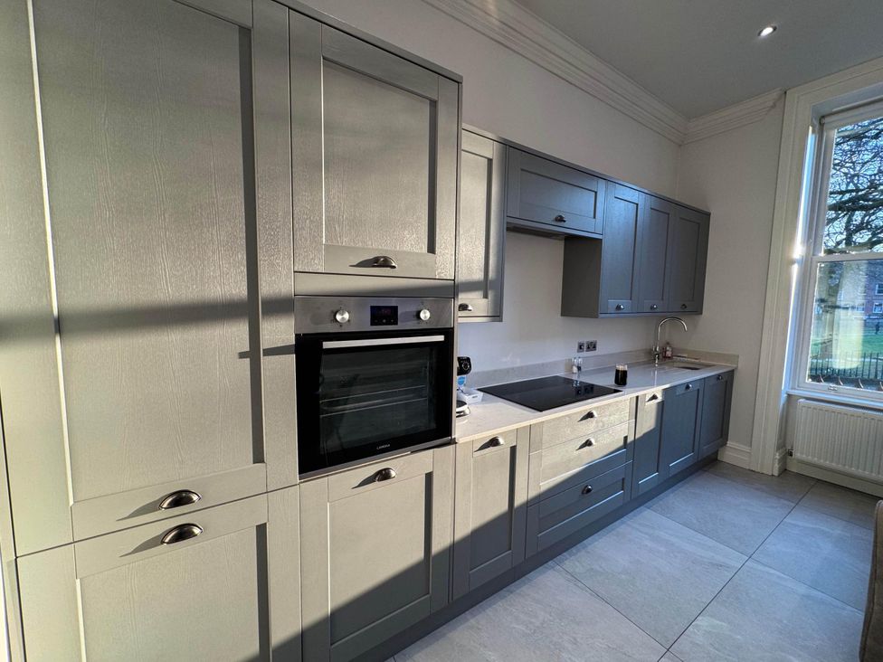 A kitchen with cabinets, an oven, a sink, and a cooktop at Apartment 2 in Preston, Lancashire