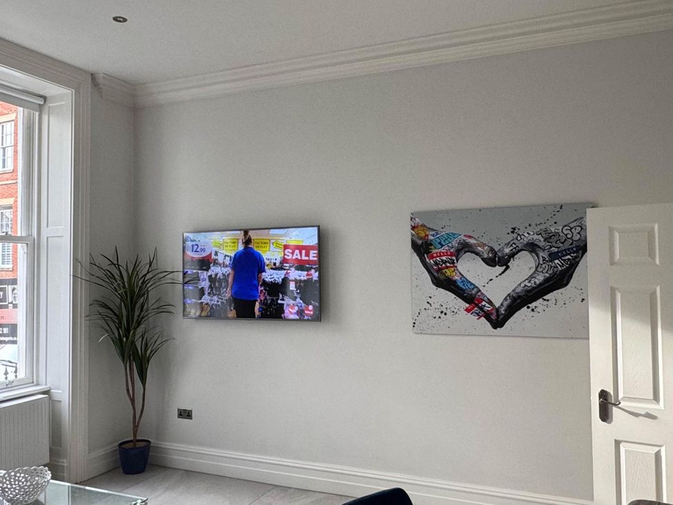 A living room with a television and artwork at Apartment 2 Preston, Lancashire