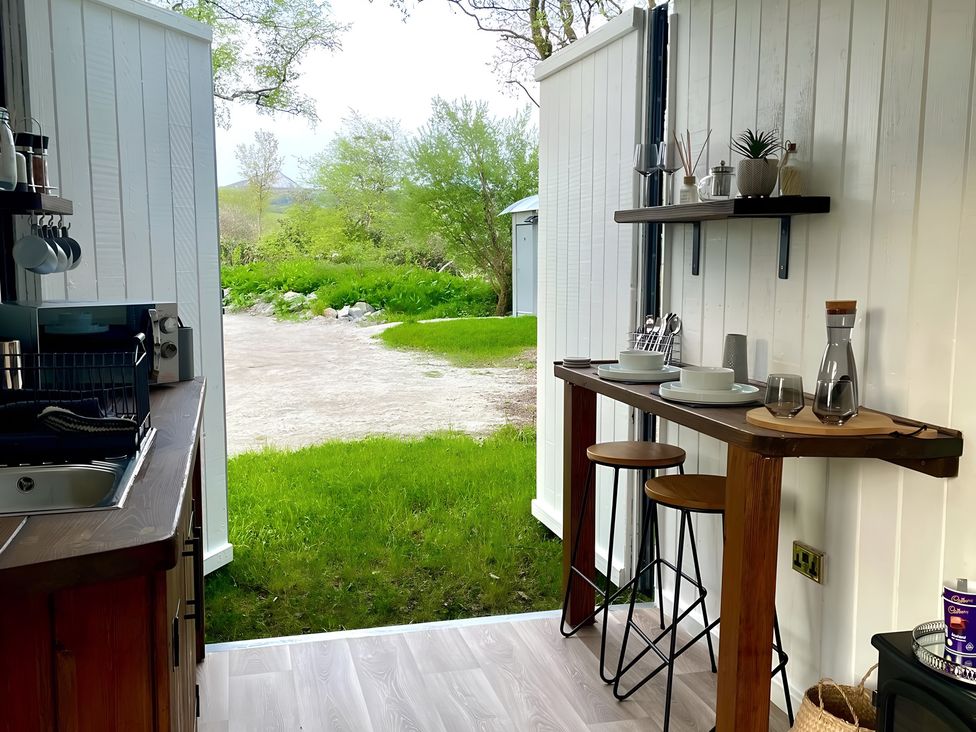 A kitchen with a wooden table and stools at Trethowels Hidden Huts in St. Austell