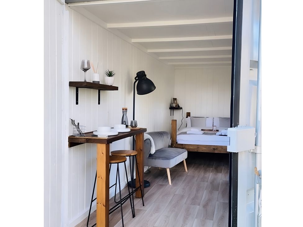 A interior view with a bed, sofa, and table at Trethowels Hidden Huts in St. Austell