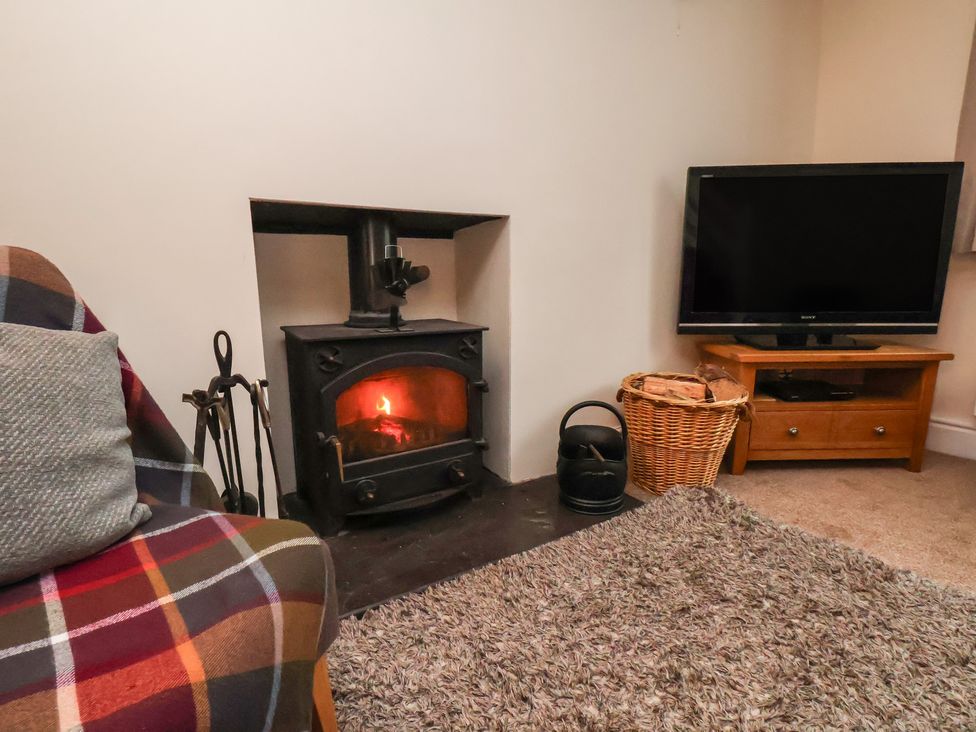 A living room with a fireplace and television at 4 Lilac Cottages