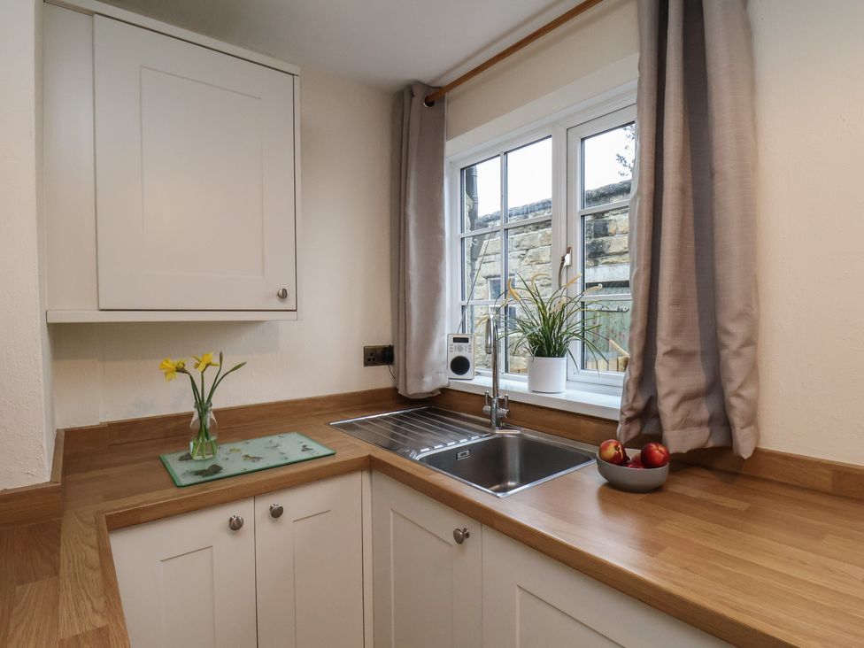 A kitchen with a sink and apples on the counter at 4 Lilac Cottages