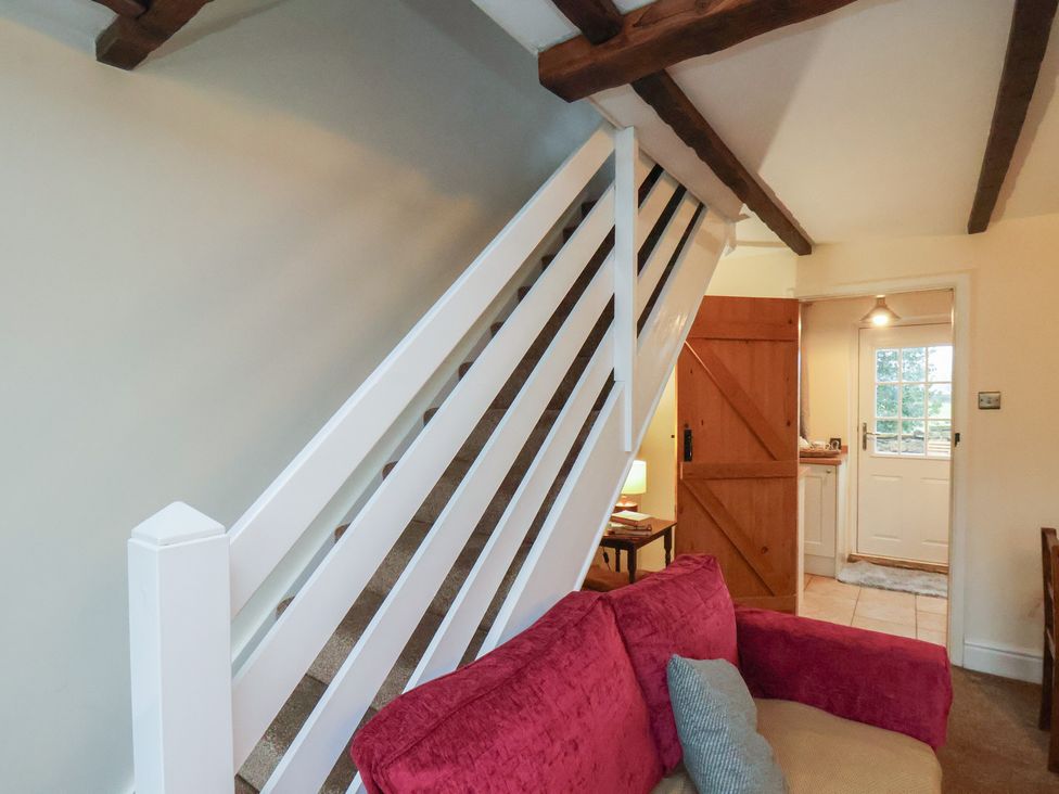A living room with a staircase and door at 4 Lilac Cottages
