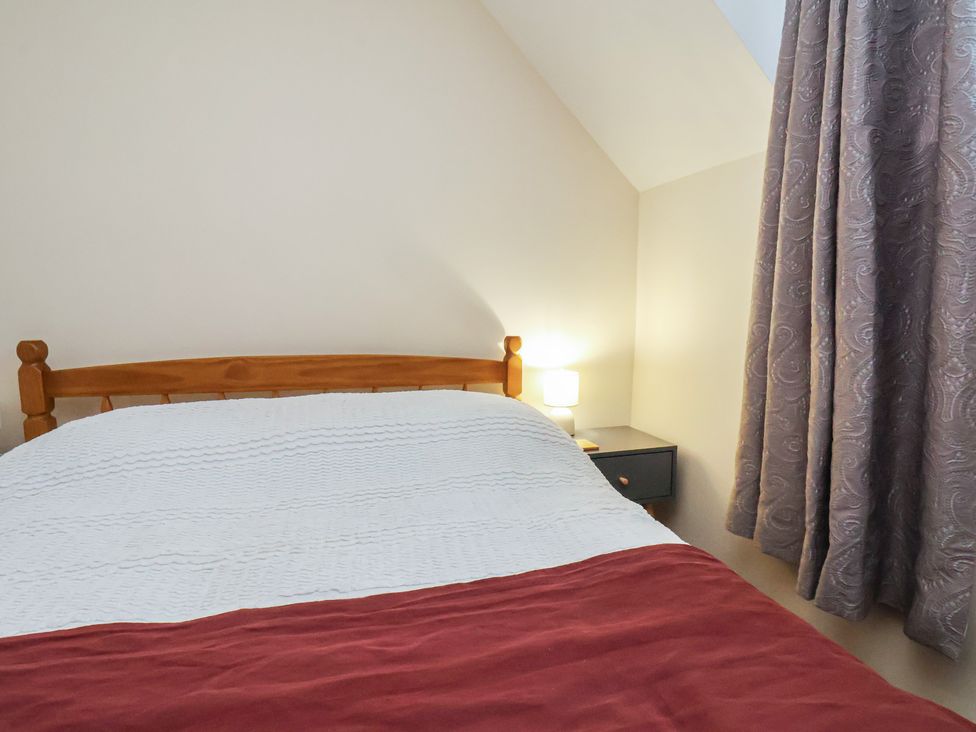 A bedroom with a bed and lamp at 4 Lilac Cottages