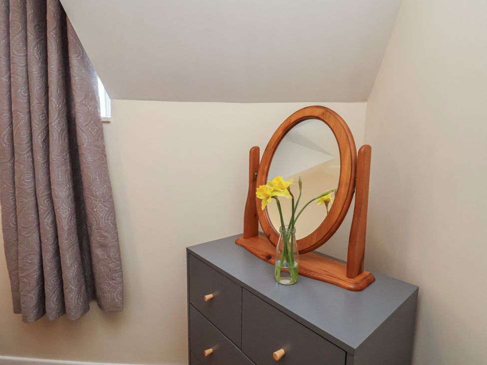 A dresser with a mirror and flowers at 4 Lilac Cottages