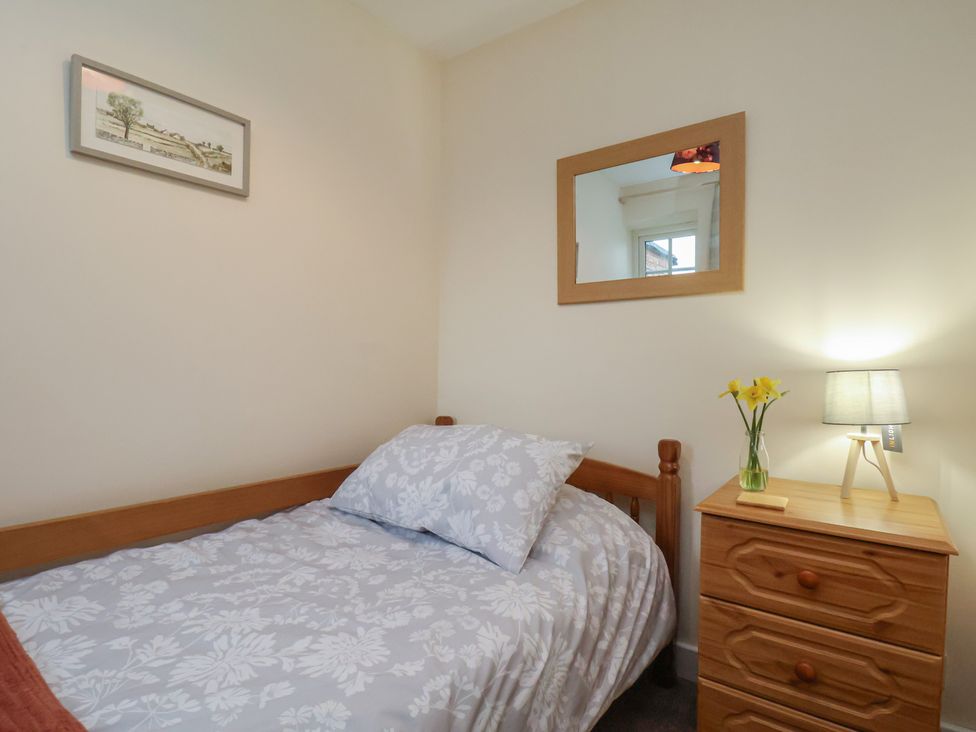 A bedroom with a bed and bedside table at 4 Lilac Cottages