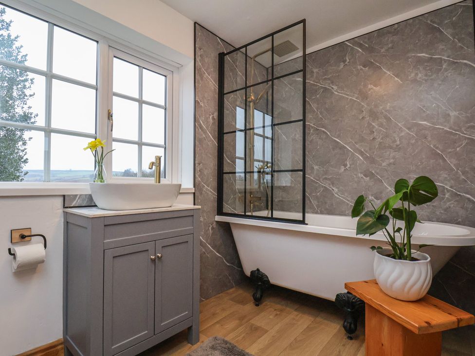 A bathroom with a bathtub and a sink at 4 Lilac Cottages