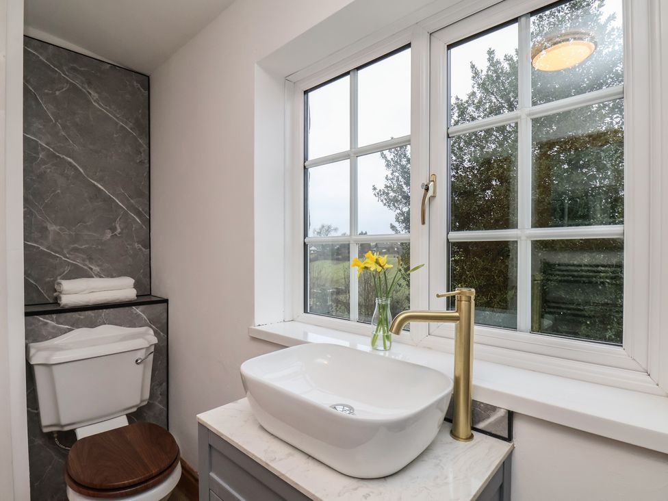 A bathroom with a sink, toilet, and window at 4 Lilac Cottages