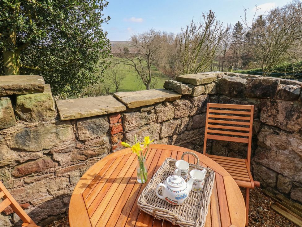 An outdoor seating area with a wooden table and chairs at 4 Lilac Cottages 