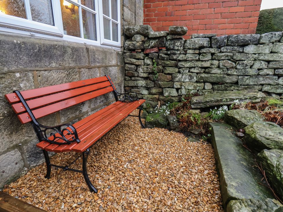 A bench with gravel and stone wall in a garden at 4 Lilac Cottages