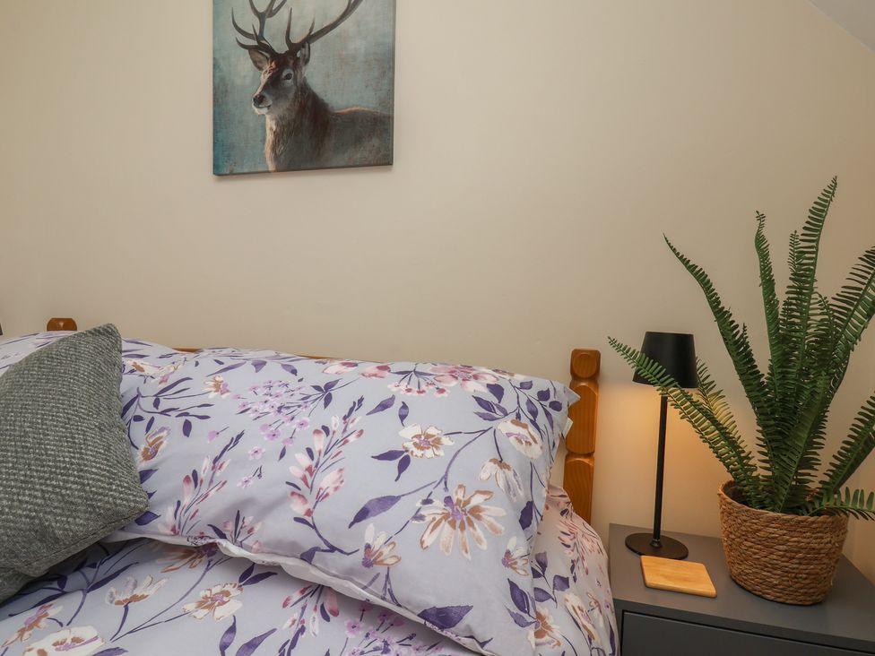 A bedroom with a bed, lamp, and plant at 4 Lilac Cottages Ainthorpe