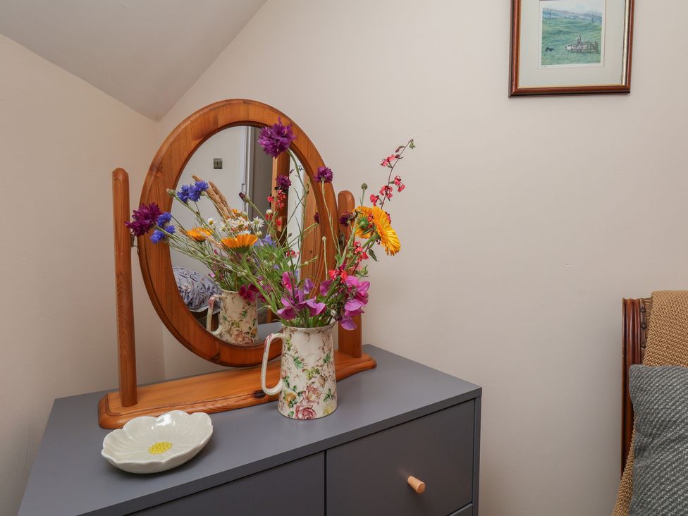 A dresser with a mirror and flowers in a vase at 4 Lilac Cottages in Ainthorpe