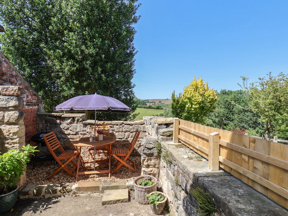 A garden with a table and chairs under an umbrella at 4 Lilac Cottages Ainthorpe