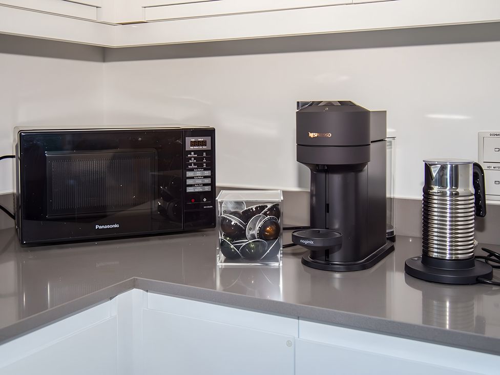 A kitchen with a microwave, coffee maker, and milk frother at Pityme-Not in Wadebridge
