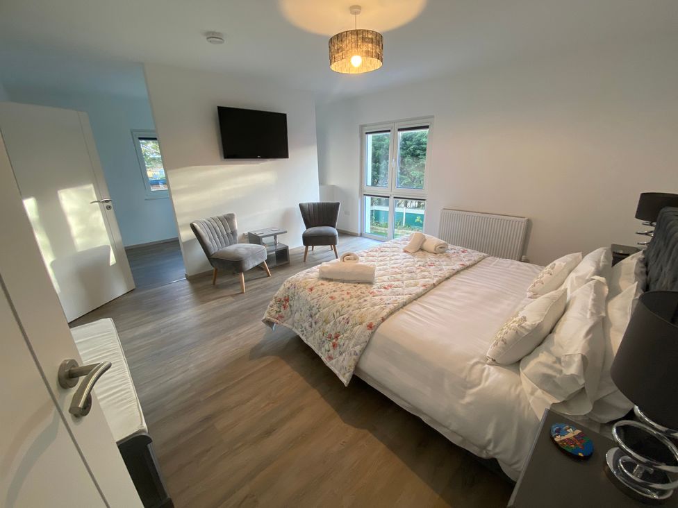 A bedroom with a bed and seating area at Pityme-Not Wadebridge