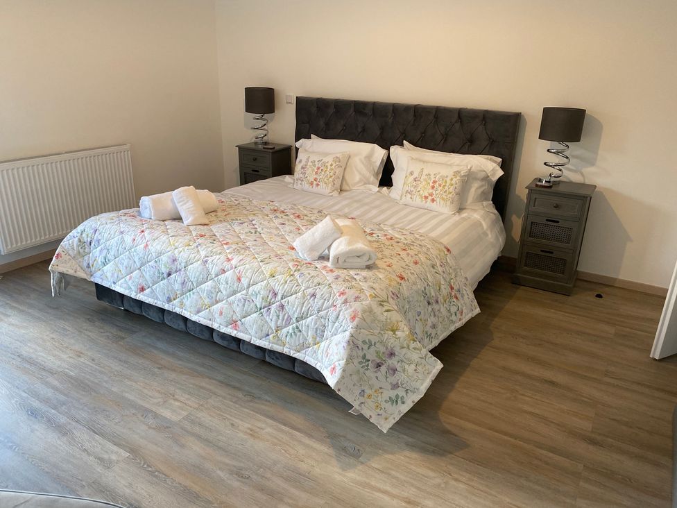 A bedroom with a bed and nightstands at Pityme-Not Wadebridge