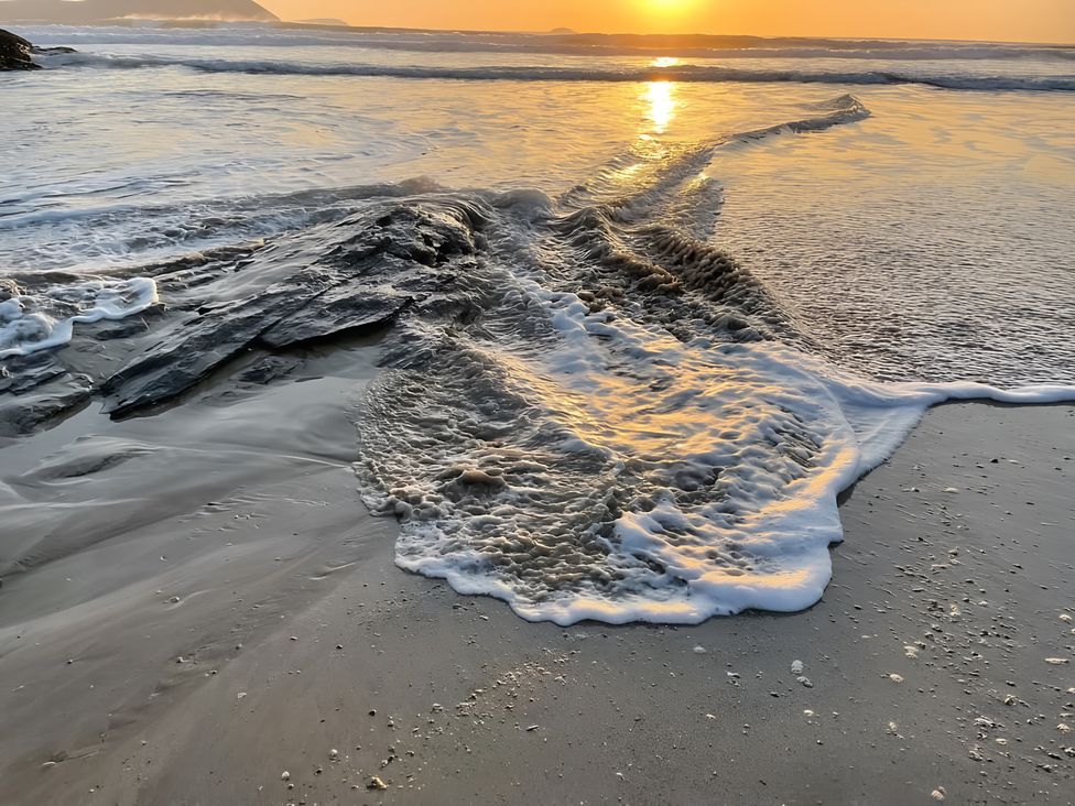 A beach with waves and rocks at Pityme-Not in Wadebridge