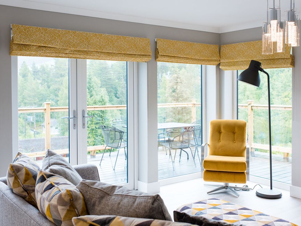 A living room with a sofa and floor lamp at Pinemarten Lodge in Crianlarich