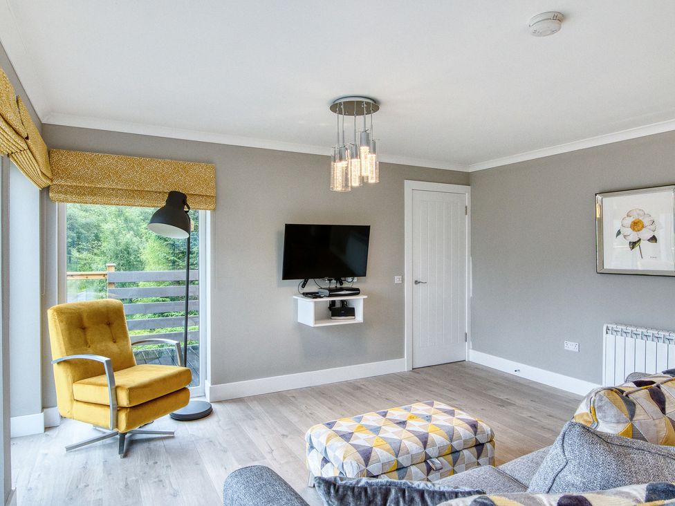 A living room with a television and seating at Pinemarten Lodge Crianlarich