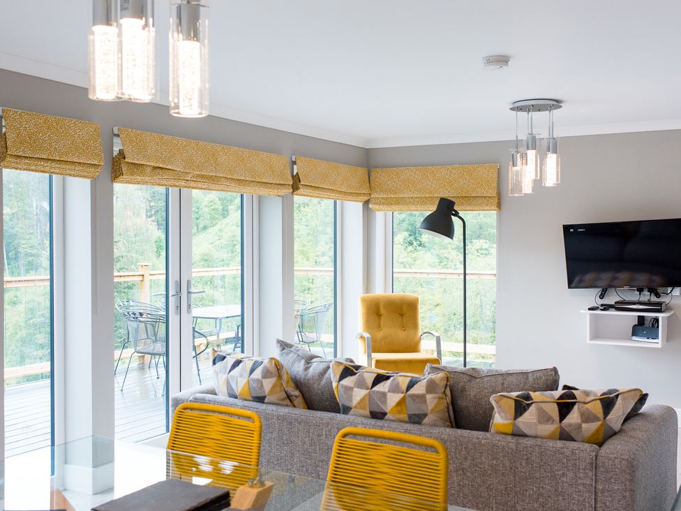 A living room with a sofa and armchair at Pinemarten Lodge Crianlarich