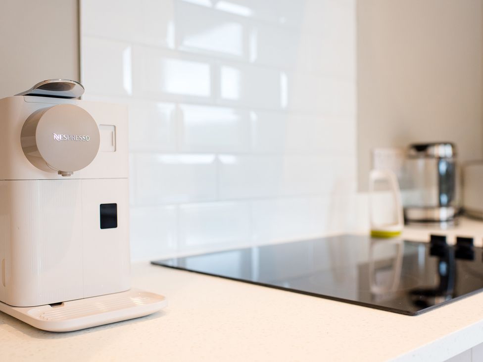 A kitchen with a Nespresso coffee maker and electric stove at Pinemarten Lodge Crianlarich