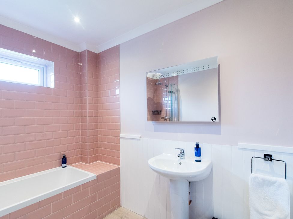 A bathroom with a bathtub and washbasin at Pinemarten Lodge Crianlarich