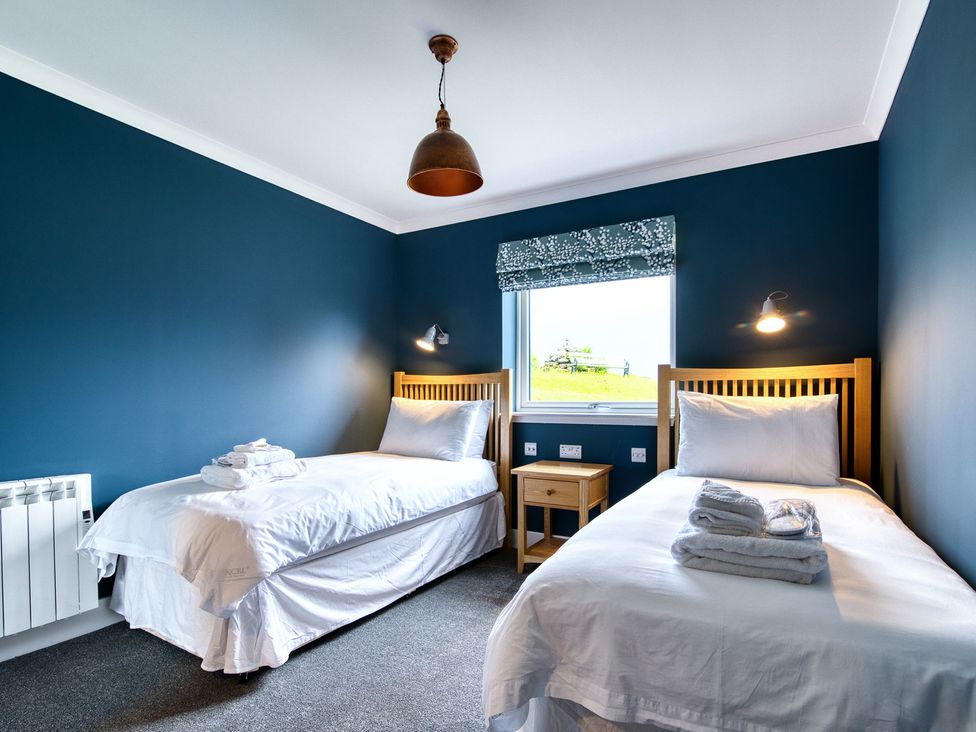 A bedroom with two beds and a table at Pinemarten Lodge Crianlarich