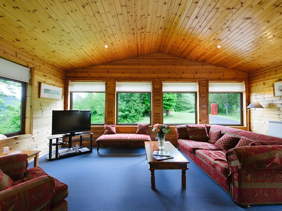 A living room with a television and sofa at Buzzard Lodge in Crianlarich