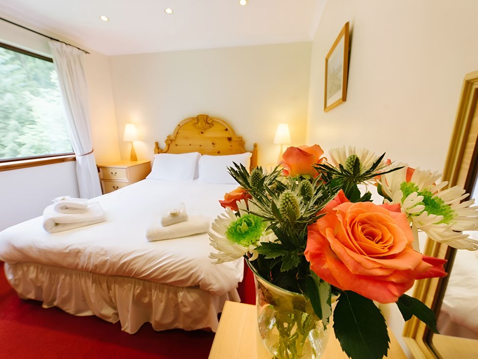 A bedroom with a bed and flowers at Buzzard Lodge in Crianlarich
