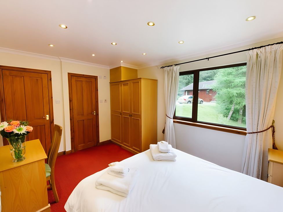 A bedroom with a bed and wardrobe at Buzzard Lodge in Crianlarich