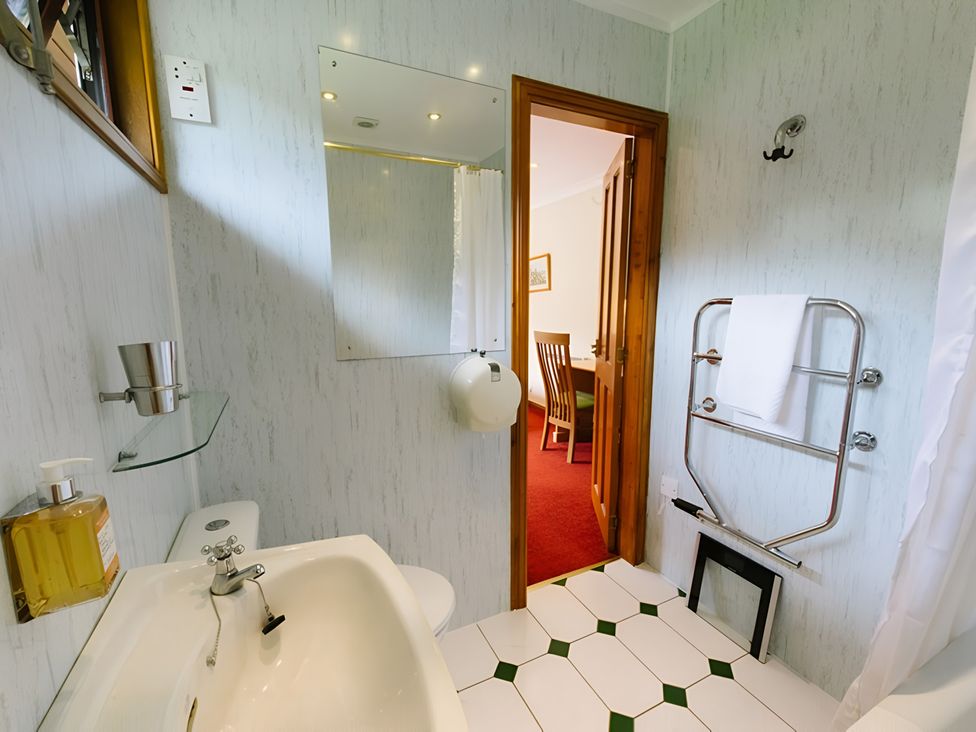 A bathroom with a sink and towel rack at Buzzard Lodge in Crianlarich