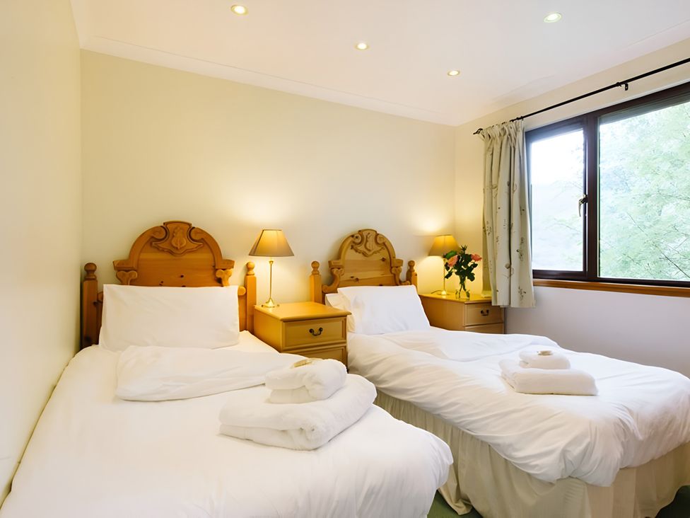 A bedroom with two beds and a nightstand at Buzzard Lodge in Crianlarich