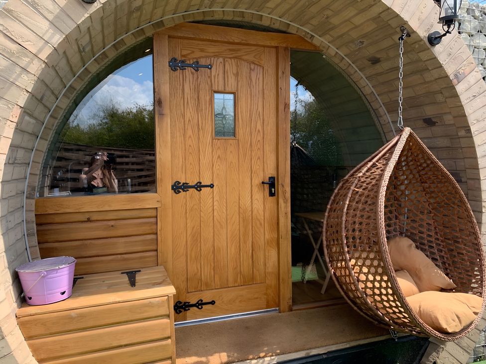 An entrance with a wooden door and hanging chair at Cosy Escape in Sheerness