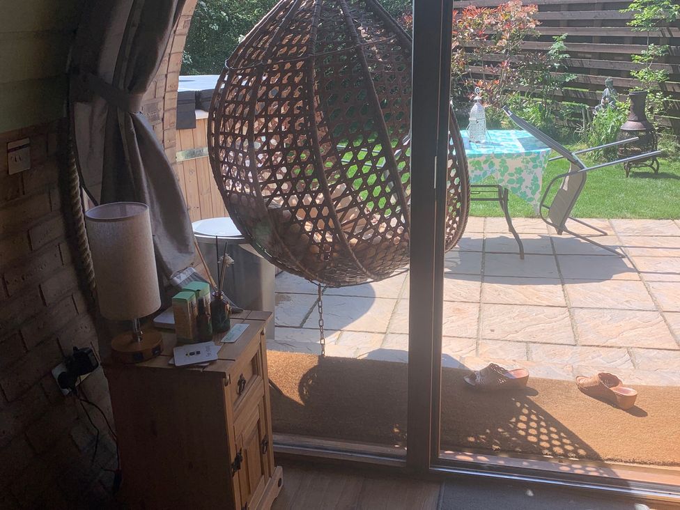 A living room with a hanging chair and outdoor view at Cosy Escape Sheerness