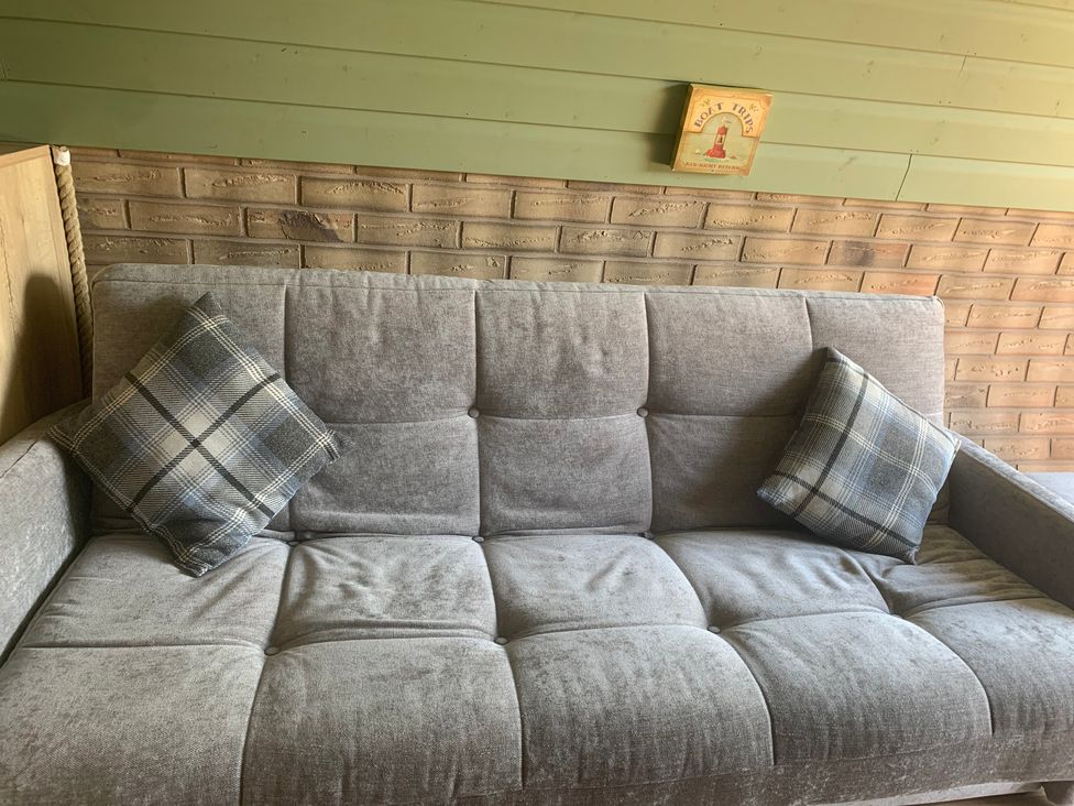 A sofa with a cushion and a wall plaque at Cosy Escape in Sheerness