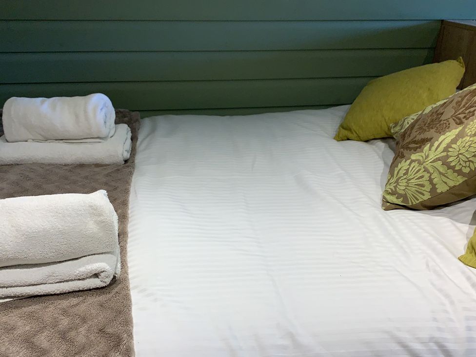 A bed with pillows and towels at Cosy Escape in Sheerness