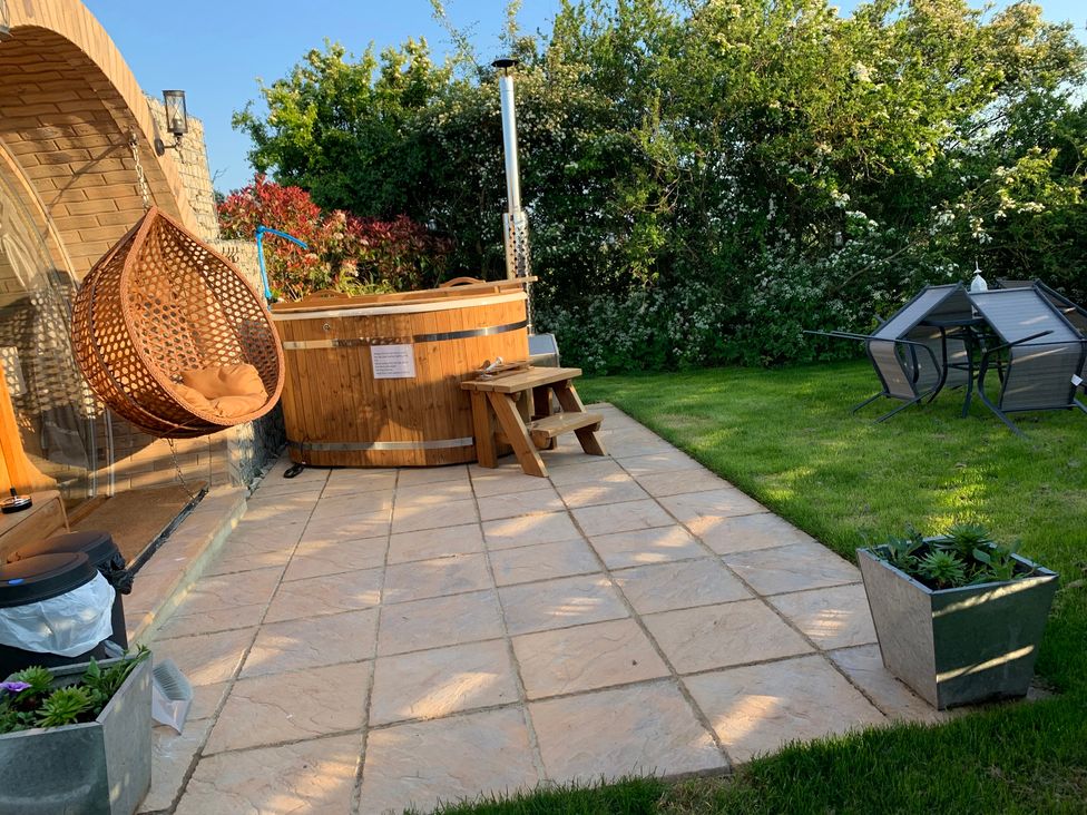 A garden with a hanging chair and hot tub at Cosy Escape in Sheerness