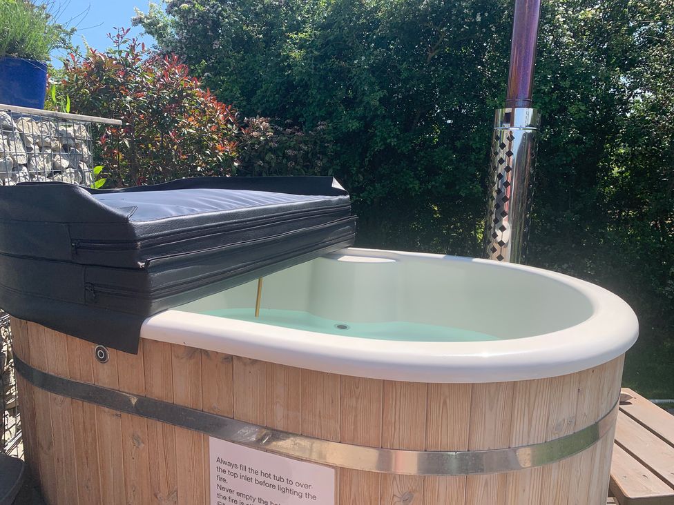 A hot tub with a cover and wooden structure at Cosy Escape in Sheerness
