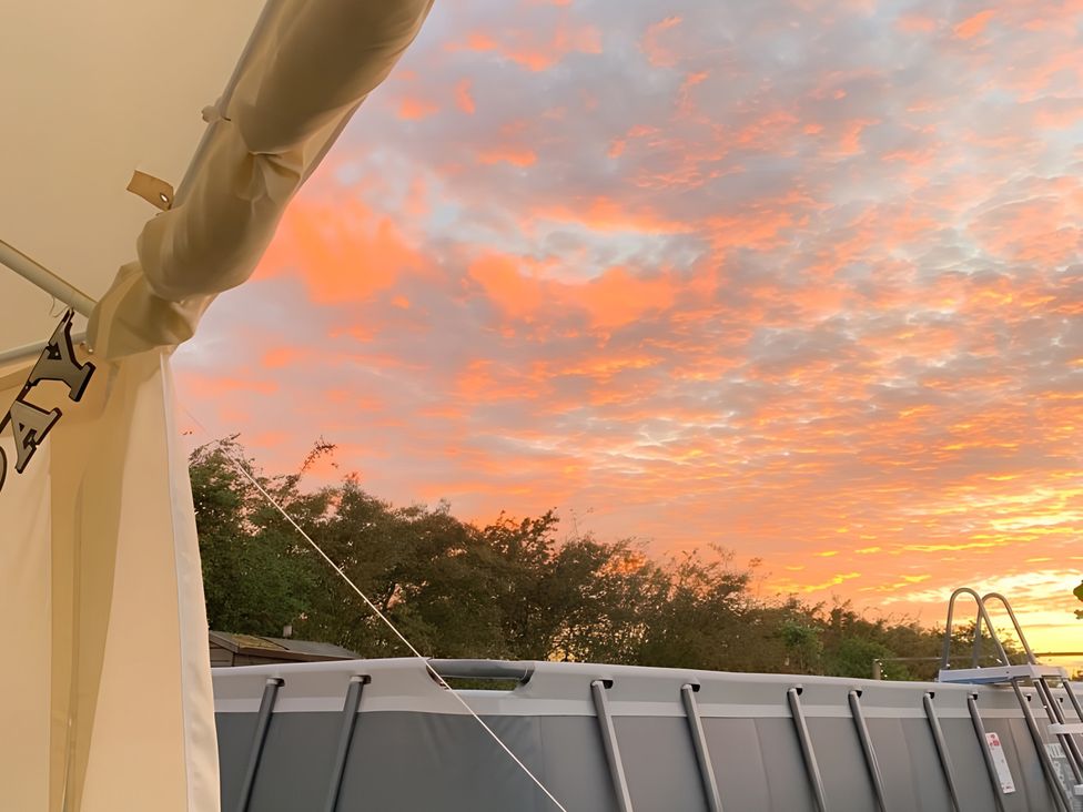 An outdoor area with a pool and trees during sunset at Cosy Escape in Sheerness