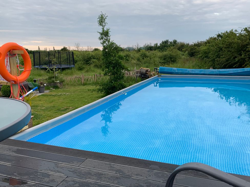 A swimming pool with a lifebuoy and trampoline at Cosy Escape in Sheerness