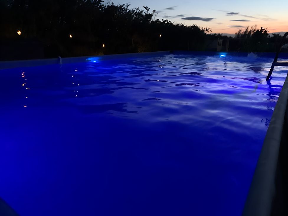 A swimming pool with blue water and lights at Cosy Escape in Sheerness